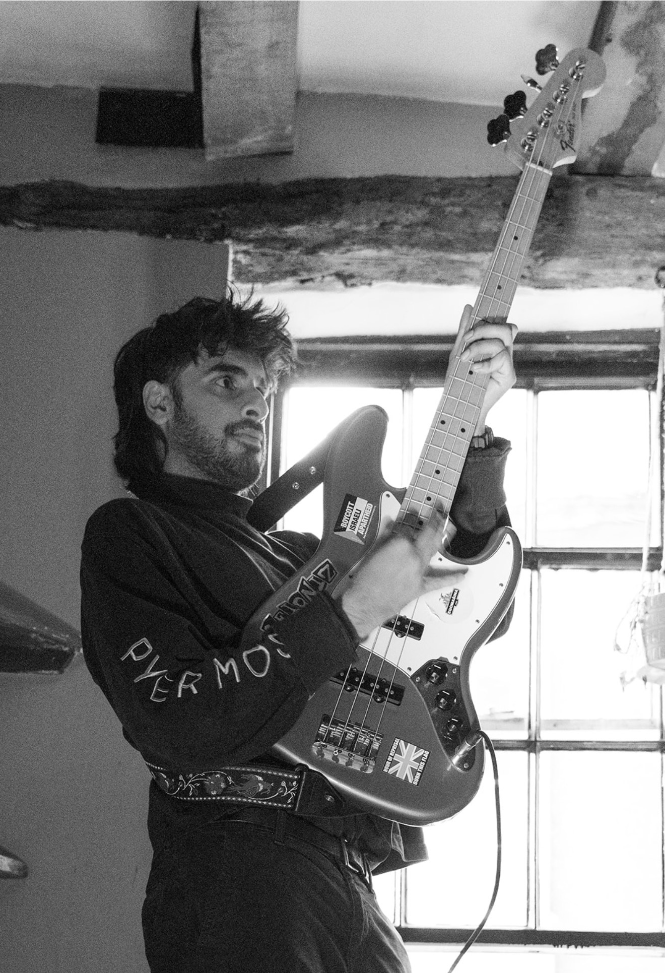 Black and white portrait of a bassist playing a Fender bass in front of a bright window