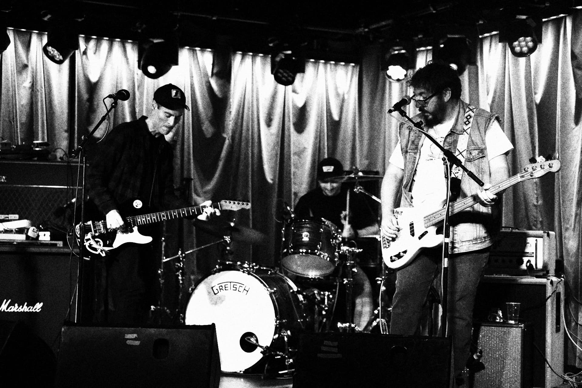 HUNCHPOWER on stage in black and white, guitarist, drummer behind a Gretsch kit and bassist at the mic