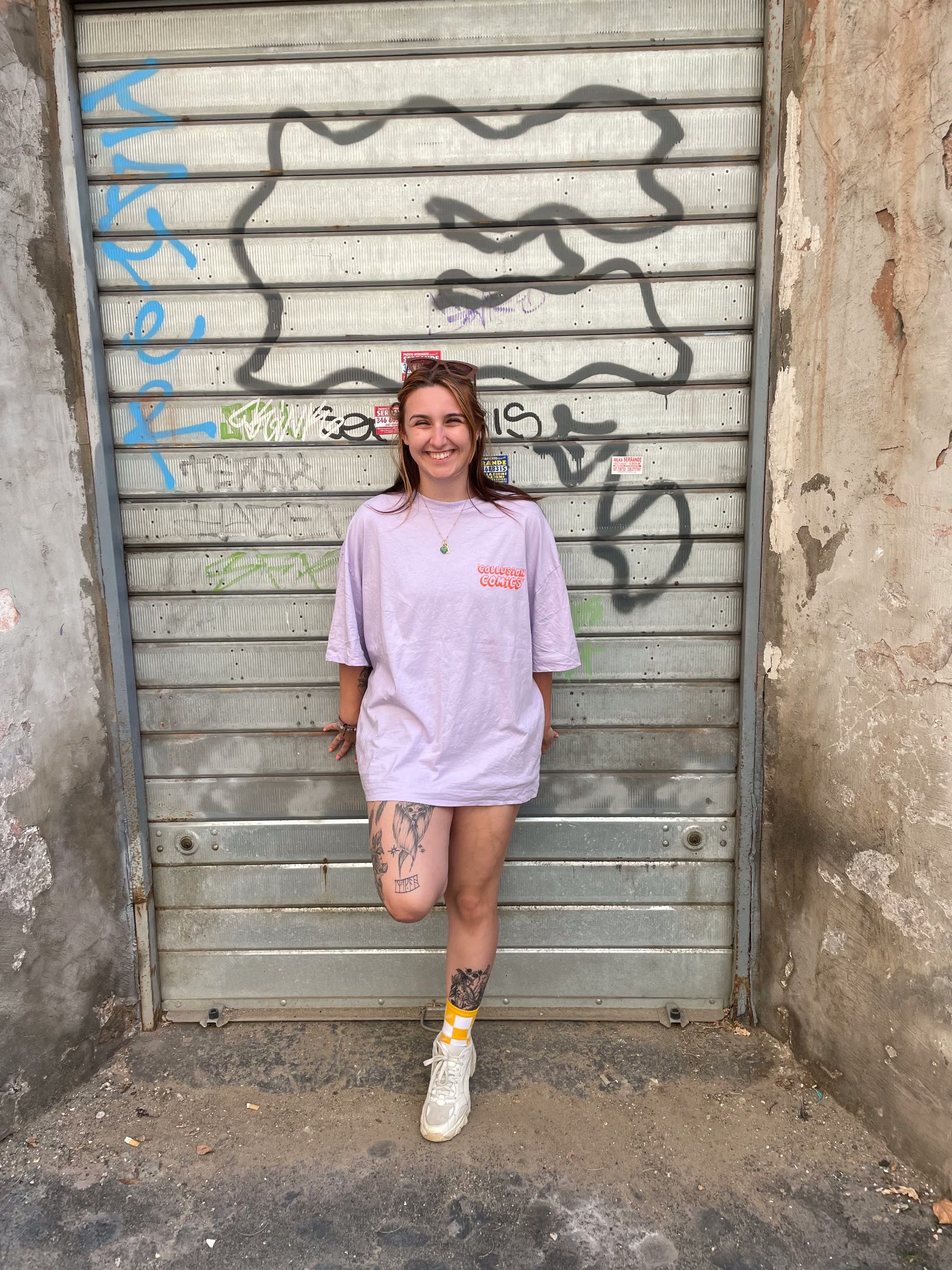 Carla smiling, leaning against a graffiti-covered metal door