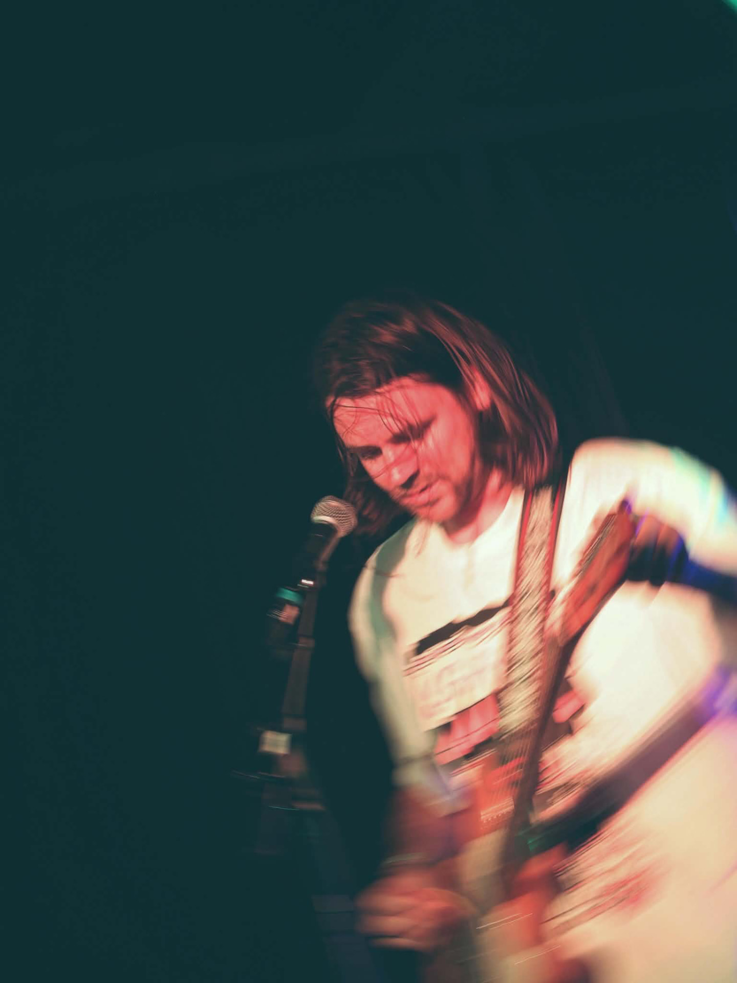 Guitarist mid-motion under teal and red stage light at The Water Rats, London