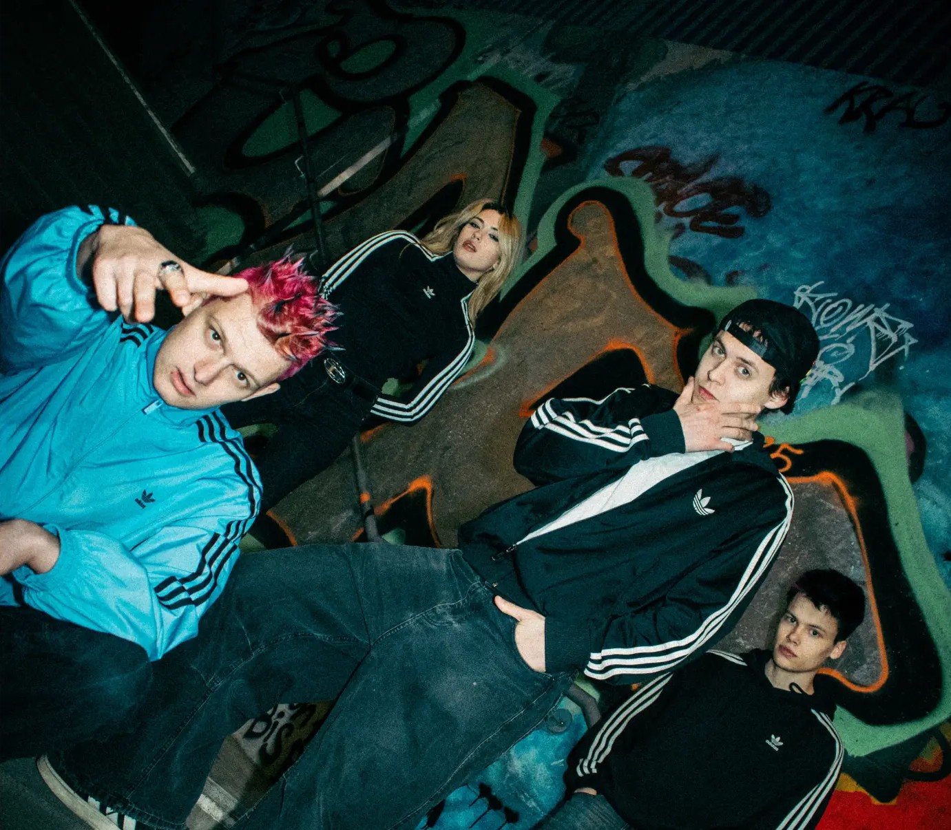 Pink Pool's four members in matching striped tracksuit tops against a graffiti-covered wall